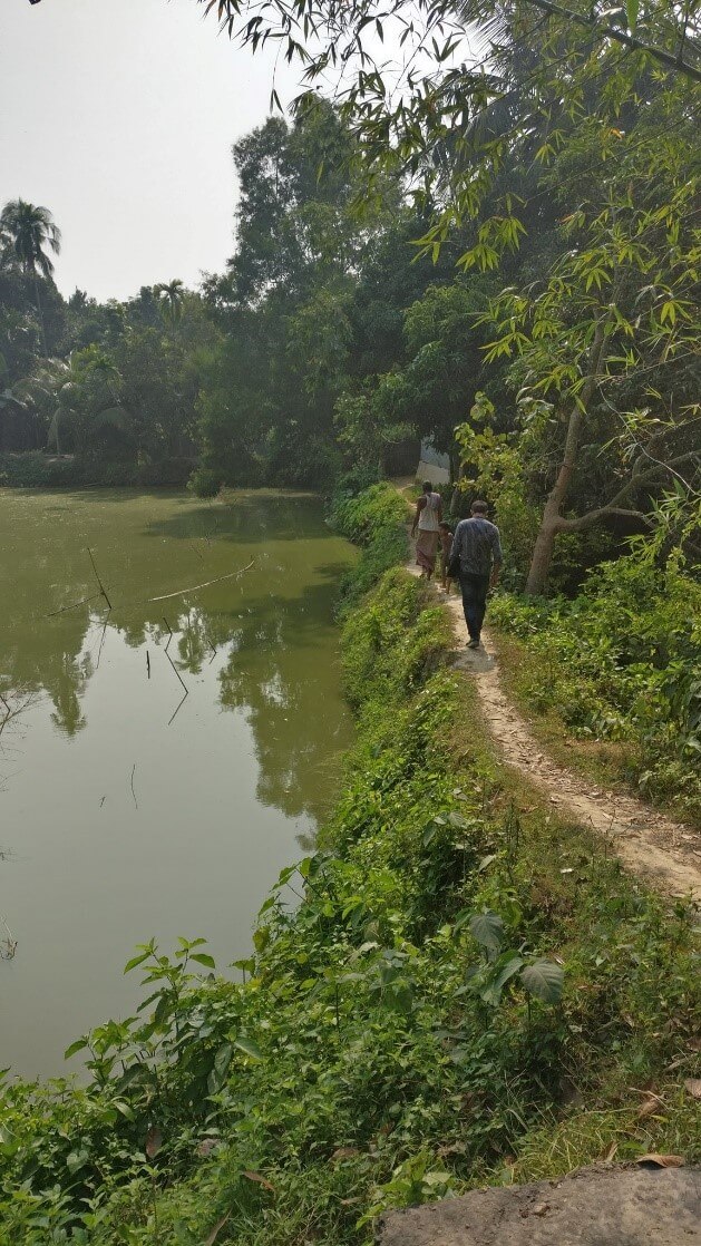 A narrow path next to a lake in Bangladesh